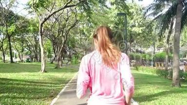 慢动作-年轻的亚洲女人早上在人行道上跑步。 年轻的亚洲运动女子在公园里跑步。