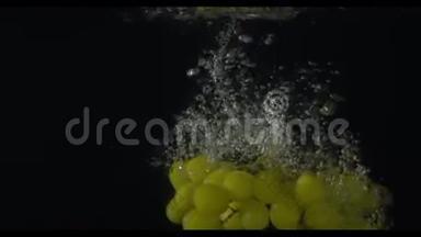 一串绿色的葡萄在镜头左侧潜<strong>入水</strong>中，黑色背景，慢动作，米/秒