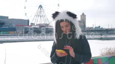 一个戴着熊猫帽的女孩在城里听音乐