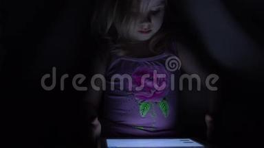 可爱的小女孩在黑暗房间的平板电脑上工作。 4K超高清，超高清