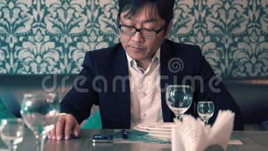 穿西装的亚洲男人在咖啡馆里等着他们的食物。 长时间等待<strong>点餐</strong>.. 紧张