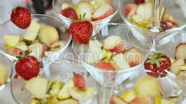 在一张白色桌子上放着草莓的玻璃杯里的水果。 庆祝活动