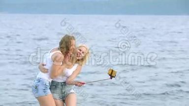 两个朋友女人用手机在河边自拍。 两个小女孩在河边玩耍，自拍