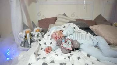 可爱的小男孩，孩子睡觉时抱着玩具，小孩子睡觉，婴儿躺在床上，躺在滑块和帽子里。