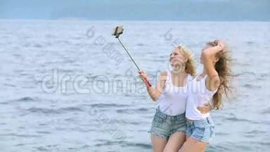 两个朋友女人用手机在河边<strong>自拍</strong>。 两个小女孩在河边玩耍，<strong>自拍</strong>