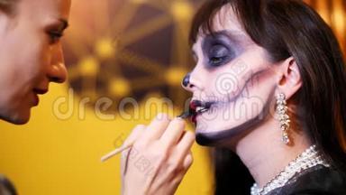 万圣节派对，化妆师在万圣节派对上给一个黑发女人的脸上画了一个可怕的妆容。 在