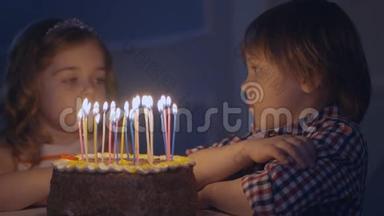 一个小男孩和一个女孩在庆祝蛋糕上看蜡烛并许愿