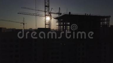 日落时的建筑工地。 建筑物附近建筑起重机的剪影