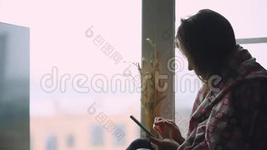 伤心体<strong>贴</strong>的女人坐在窗台上，一边用手机看着窗户。 1920x1080。