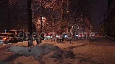 白雪覆盖的<strong>街道</strong>，有美丽的树木和雪堆，在路灯的灯光下通过<strong>车辆</strong>。