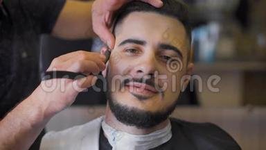 沙龙里的嬉皮士发型。 专业理发师使用直剃须刀制作胡须趋势形态..