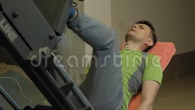 一个超重的男人在健身房里用模拟机做腿部按压。健身训练。健康生活方式理念