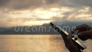 日出时分，一个男人在海边查看平板电脑上的信息。<strong>绚丽</strong>的天空和朝阳