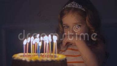 一个小<strong>女孩</strong>看着节日蛋糕上的蜡烛，慢慢地<strong>许愿</strong>