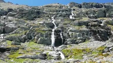 瀑布在田园诗般的无污染环境中流动，夏天穿过阿尔卑斯山上的绿色草地和巨石。