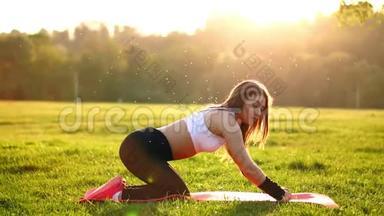 年轻漂亮的女人正在休息时坐在<strong>垫子</strong>上健身。 运动后在阳光下休息