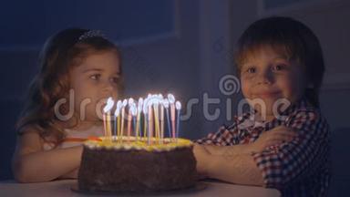 一个小男孩和一个<strong>女孩</strong>在庆祝蛋糕上看蜡烛并<strong>许愿</strong>