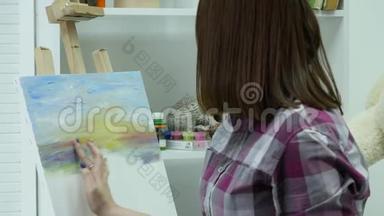 艺术家在画布上画一个女人，并涂上一层宽的画笔。 帆布站在画架上。 画家在画架上画画