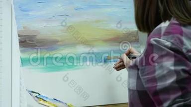 艺术家在画布上画一个女人，并涂上一层宽的画笔。 帆布站在画架上。 画家在画架上画画