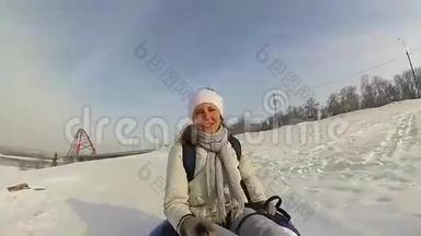 快乐的女孩骑着雪管在雪道上微笑。 慢动作。 冬天的雪景。 户外运动