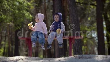 坐在长凳上吃香蕉的两个小孩子