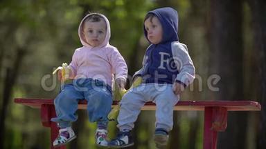 坐在长凳上吃香蕉的两个小孩子