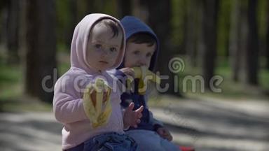 坐在长凳上吃香蕉的<strong>两个小孩子</strong>