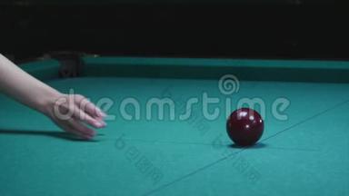 女孩的手把球放在台球桌上。 前景中的大红台球