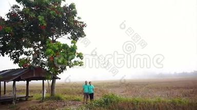 视频亚洲资深夫妇站在<strong>凉亭</strong>旁边，中间雾蒙蒙的稻田。 农业和农业企业