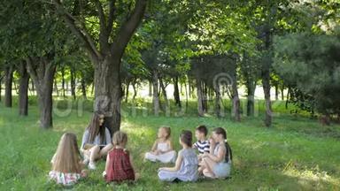 儿童和教育，年轻妇女在工作中，作为教育者向公园的男孩和女孩读书