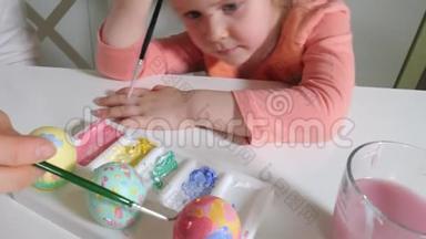 母亲和女儿用彩色颜料画复活节彩蛋
