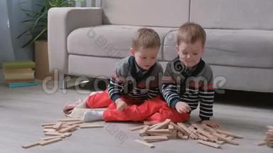 双胞胎兄弟正在用坐在他们房间里沙发旁的木块建造一座塔。