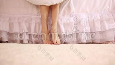 卧室里有柔软皮肤的女人腿。 女人下床