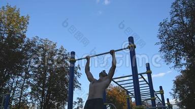 强壮的<strong>肌</strong>肉男在公园里做<strong>肌</strong>肉锻炼。 年轻运动员在户外<strong>水</strong>平杆上做下巴练习。 健身