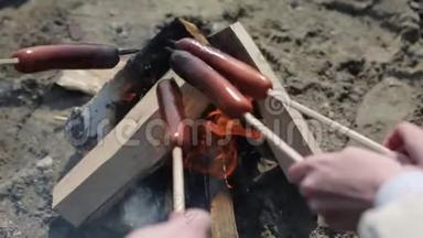 在露天篝火上制作和烹饪热狗香肠。