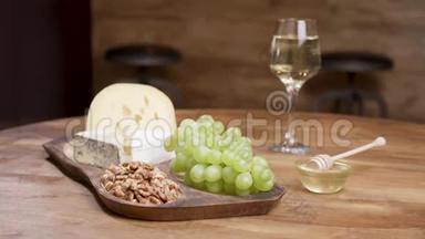 奶酪和葡萄放在木桌上，上面有蜂蜜、核桃和葡萄酒