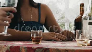 女孩坐在房子里的露台上，端着饮料。 穿白衬衫的人拿玻璃