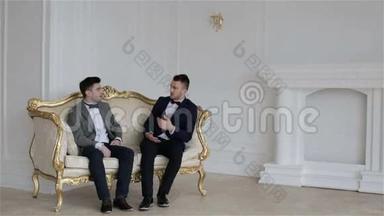 两个年轻英俊的男人坐在一张<strong>老式沙发</strong>上。