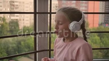 美丽可爱快乐的小女孩在无线耳机上听音乐。 有趣的小女孩唱着歌