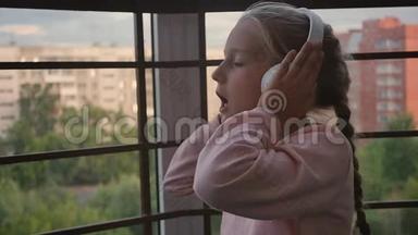 美丽可爱快乐的小女孩在无线耳机上听音乐。 有趣的小女孩唱着歌