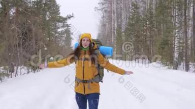 女<strong>游客</strong>走在冬天的<strong>森林</strong>路上，肩上背着一个背包。