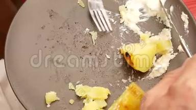 烤香肠和土豆用不锈钢刀叉在盘子里切