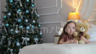 一个女人<strong>躺在床上</strong>，一只玩具熊<strong>躺在</strong>圣诞树旁