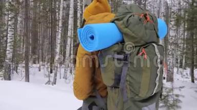 女<strong>游客</strong>走在冬天的<strong>森林</strong>路上，肩上背着一个背包。