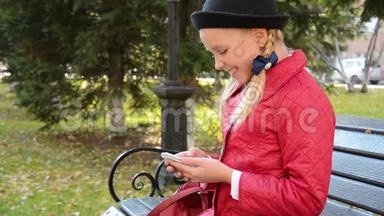 <strong>今年</strong>秋天，城市公园的一位年轻女孩在智能手机上使用应用程序坐在长椅上