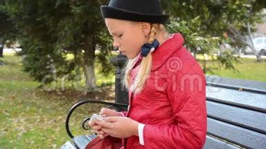 今年秋天，城市公园的一位年轻女孩在智能手机上使用应用程序坐在长椅上