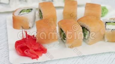 新鲜美味的寿司，里面有三文鱼、生姜、奶酪和芥末，放在咖啡厅的白色盘子里