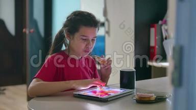 少女正在吃三明治，在平板电脑上玩一个<strong>网络</strong>游戏。 <strong>女孩社交</strong>媒体平板电脑互联网