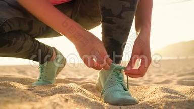 跑鞋-日落时分在沙滩上系鞋带的女人
