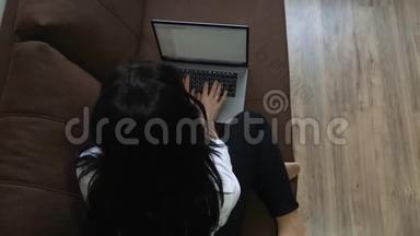 坐在沙发上用笔记本电脑的年轻女子
